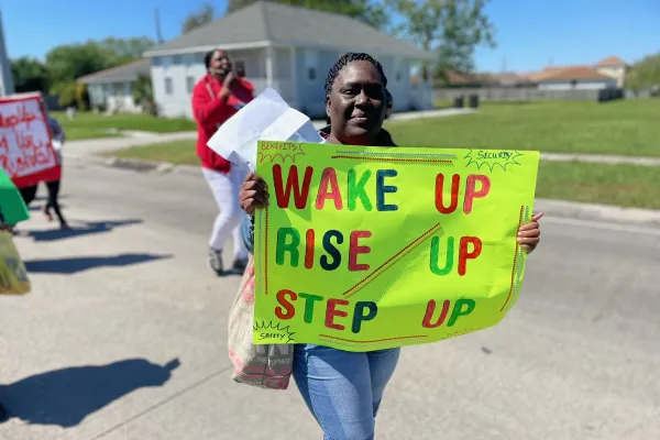 A worker holds a sign that says "Wake up. Rise up. Step up."